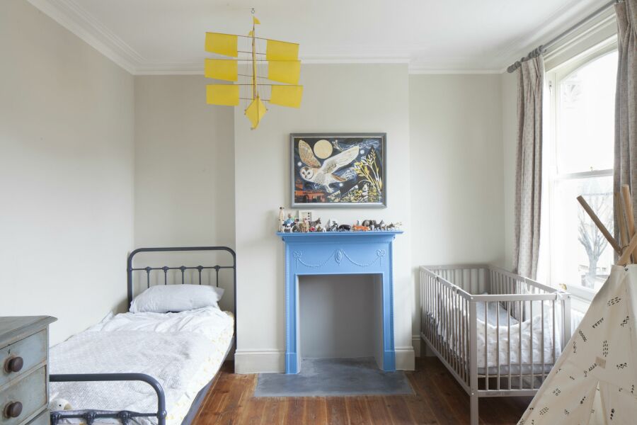 Pale coloured child's bedroom with a bed and a cot.