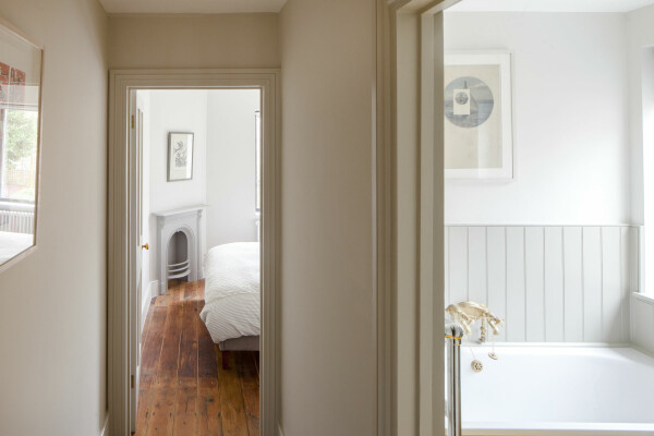 Hallway with pale, earthy paint tones looking through to a bedroom and a bathroom