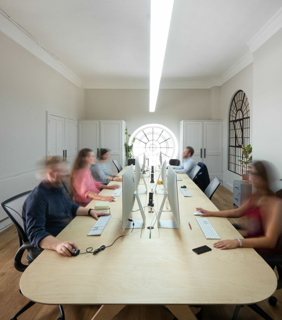 People working at a desk, they are blurred due to slow shutter speed.